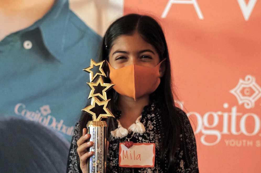 Little girl smiling with a trophy after winning a debate competition - Cogito Debate